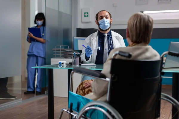 Incontro medico con una donna in pensione in sedia a rotelle alla visita di controllo — Foto Stock