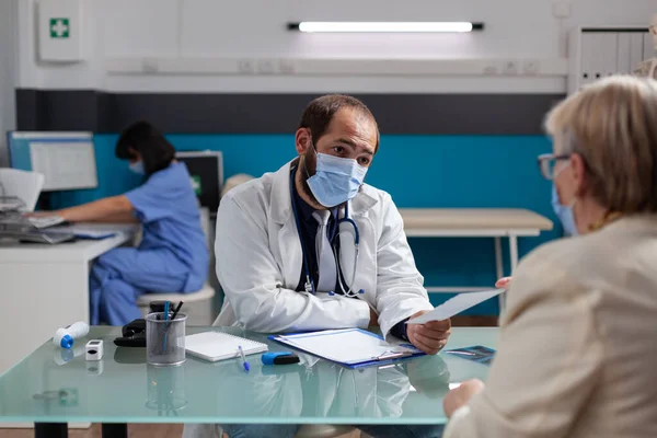 Specialist giving prescription paper to pensioner at appointment — Stock Photo, Image