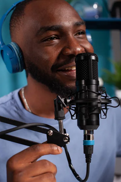 Primo piano del vlogger sorridente che parla al pubblico utilizzando un microfono professionale con cuffie wireless — Foto Stock