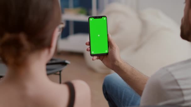 Primo piano della coppia che tiene lo smartphone verticale con schermo verde in conferenza online o videochiamata di gruppo — Video Stock