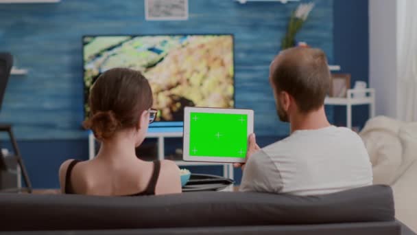 Pareja relajándose en el sofá mirando el contenido de vídeo de las redes sociales utilizando la tableta digital con pantalla verde — Vídeo de stock