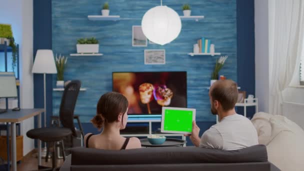 Pareja en el sofá viendo espectáculo en línea utilizando la aplicación de streaming en la tableta digital con pantalla verde — Vídeo de stock