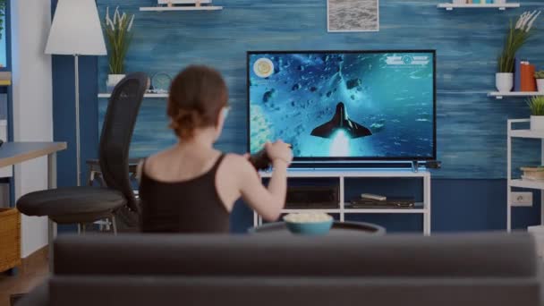 Elinde kablosuz kontrol cihazı olan oyuncu kız TV 'de konsol oyunu oynuyor. — Stok video