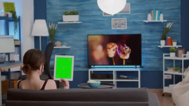 Çevrimiçi konferansta veya grup video çağrısında yeşil ekranlı dikey dijital tablet tutan kız
