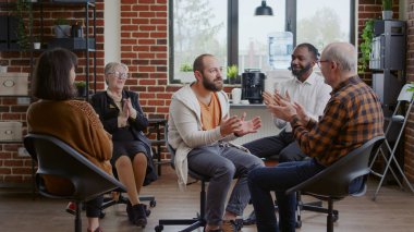 A.A. toplantısında terapi sürecini grupla paylaştıktan sonra alkış ve tebrik alan adam.