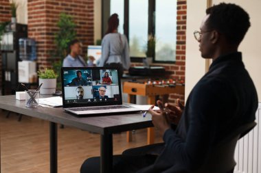 Pazarlama bürosu çalışanı dijital video görüşmesinde iş arkadaşlarıyla konuşuyor.