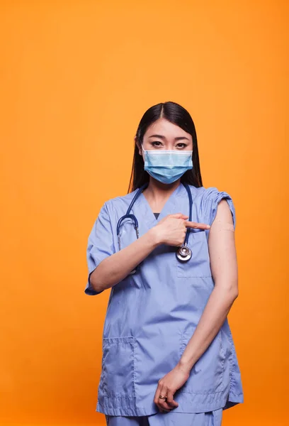 Responsible healthcare nurse promoting vaccination against coronavirus epidemic while wearing a band aid. — 스톡 사진