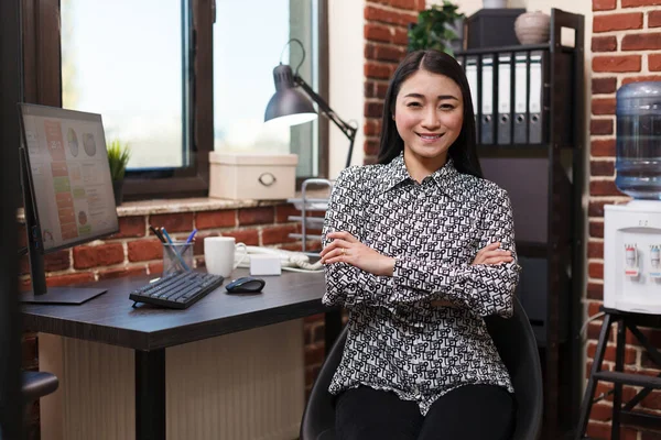 Felice sorridente asiatico businesswoman seduta a scrivania in finanza società ufficio sul posto di lavoro mentre guardando fotocamera. — Foto Stock