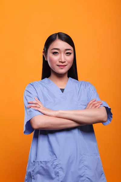 Portret pięknej azjatyckiej młodej pielęgniarki w niebieskim mundurku medycznym patrząc w kamerę. — Zdjęcie stockowe