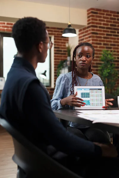 Mujer de negocios afroamericana que presenta a sus compañeros de trabajo datos estadísticos de documentación contable en tableta. —  Fotos de Stock