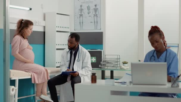Médico afro-americano escrevendo relatório de check-up em arquivos — Vídeo de Stock
