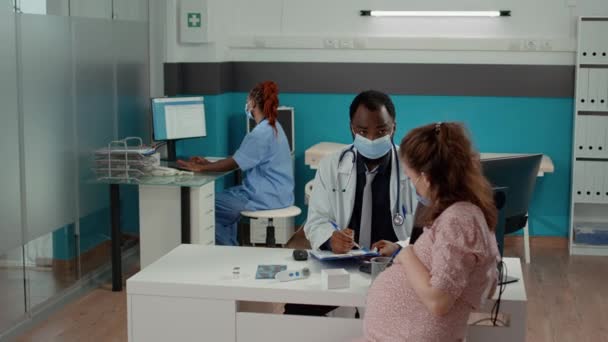 Ιατρός συμβουλεύεται τη μελλοντική μητέρα και λαμβάνει σημειώσεις υγειονομικής περίθαλψης — Αρχείο Βίντεο