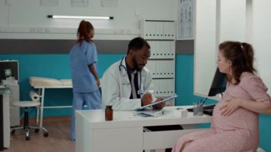 Doktor hamile birine danışıyor ve not alıyor.