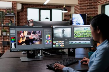 Yaratıcı şirket profesyonel film görüntüleme editörü film çerçevelerini düzenlerken çoklu monitör çalışma istasyonunda oturuyor.