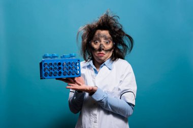 Dağınık saçlı, kirli suratlı, plastik test tüpleri taşıyan kaçık bir kimyager.