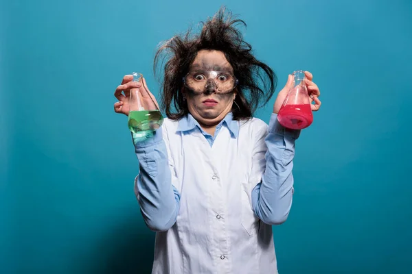 Mad chemist with dirty face and messy hair having flasks filled with unknown chemical substances. — стоковое фото