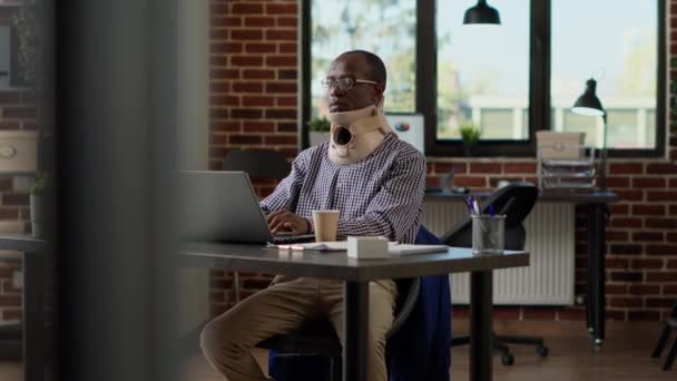 Zakenman met medische halsband aan het werk op laptop — Stockvideo