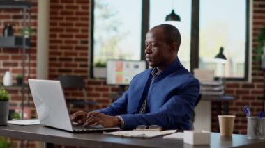 Afrikalı Amerikalı iş adamı dizüstü bilgisayardan not alıyor