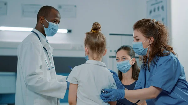 Assistente médico consultando criança pequena com estetoscópio — Fotografia de Stock