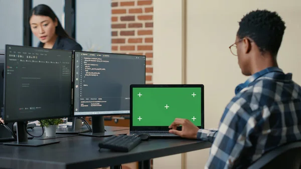 Código de escrita de designer de banco de dados usando laptop com tela verde chroma chave mockup sentado na mesa — Fotografia de Stock