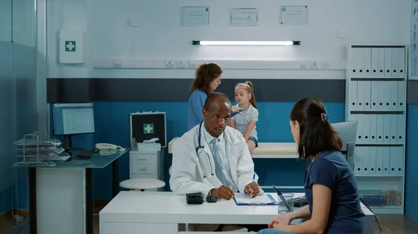 Medico avendo conversazione con adulti in gabinetto medico — Foto Stock