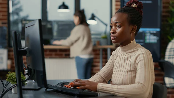 Ingeniero de software afroamericano trabajando enfocado en la pantalla de la computadora mientras escribe —  Fotos de Stock