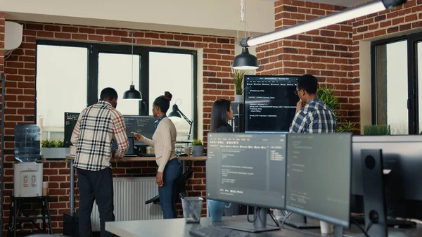Desenvolvedores de sistema analisando código na tela da parede tv procurando por erros — Fotografia de Stock