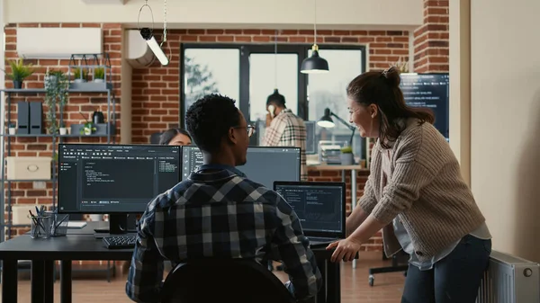 Two software developers doing high five hand gesture at desk with multiple screens running ai code — Photo