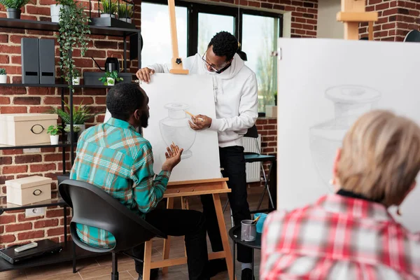 艺术课期间，年轻的画家老师帮助学生学习绘画过程 — 图库照片