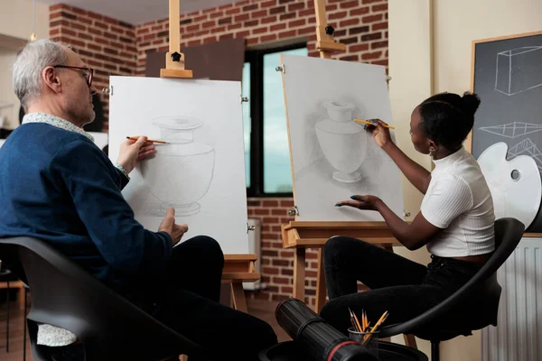 Старший вчитель контролює молодого студента під час уроків малювання — стокове фото