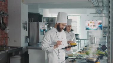 Dokunmatik ekranda online yemek tarifini takip eden bir erkek şef.