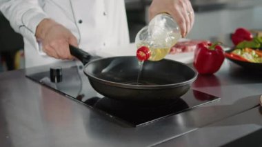 Otantik aşçı kızartma tavasına organik zeytinyağı ekliyor.
