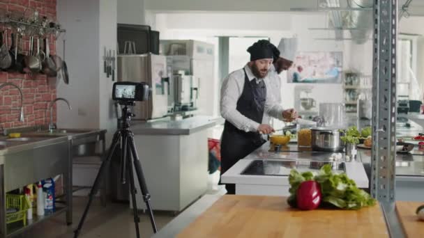Giovane uomo che spiega piatto gourmet sulla macchina fotografica per lo spettacolo di cucina — Video Stock