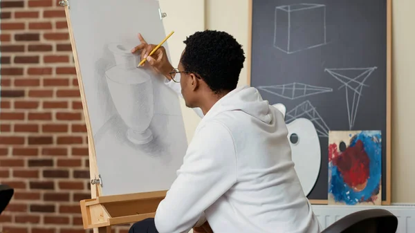 Estudiante afroamericano usando lápiz para dibujar jarrón sobre lienzo —  Fotos de Stock