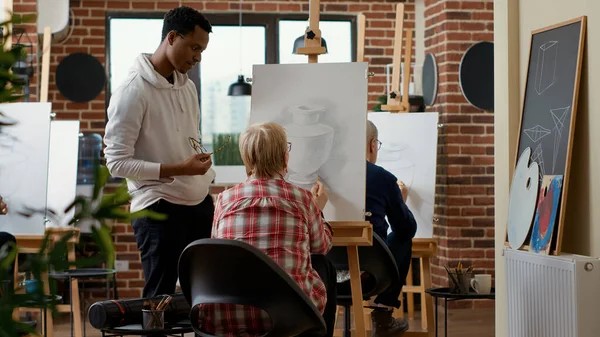 Profesor dando consejos a la mujer mayor en la clase de dibujo — Foto de Stock