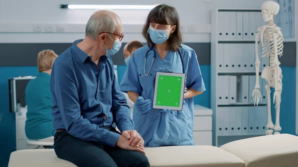 Sjuksköterska och pensionerad man tittar på grön skärm på digital surfplatta — Stockfoto