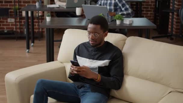 Mladý muž pomocí smartphonu na textové zprávy a procházet internet — Stock video