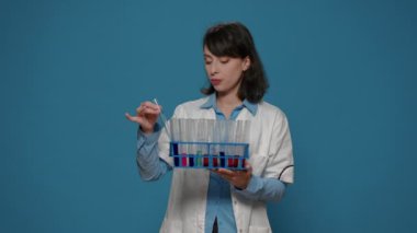 Biyoloji araştırmacısı sıvı maddeli test tüplerine bakıyor.