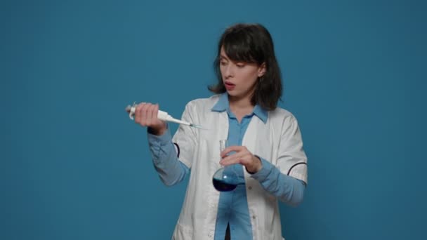 Mulher cientista usando micro pipeta para gotejar líquido em copo — Vídeo de Stock