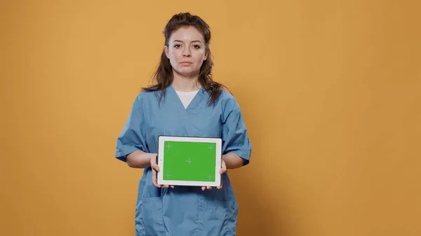 Porträtt av kvinnlig läkare håller tablett dator med grön skärm bär sjukhus uniform för vård koncept — Stockfoto
