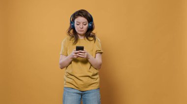 Rahatlatıcı kadının portresi akıllı telefon kullanarak kablosuz kulaklıkla müzik dinleyerek dans etmeye başlıyor.