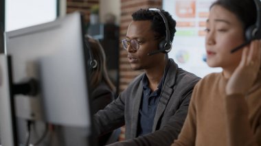 Erkek çağrı merkezi operatörü insanlara yardım etmek için kulaklık kullanıyor