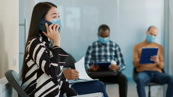 Asyalı kadın telefonda konuşuyor ve iş görüşmesine katılmayı bekliyor. — Stok fotoğraf