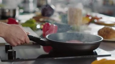 Erkek aşçı, ayçiçeği yağıyla biftek pişiriyor.