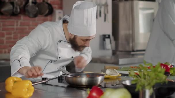 Mužský kuchař nalévání strouhaného sýra na vařené jídlo v pánvi — Stock video