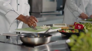 Afrikalı Amerikalı aşçı tahtanın üzerinde sarımsak karanfili hazırlıyor.