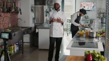Afrikalı Amerikalı aşçı kamerada yemek pişirme vlog 'u çekiyor.