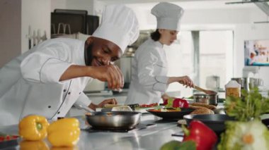 Afrikalı Amerikalı aşçı dilimlenmiş parmesan peyniri döküyor.