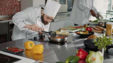 Otantik aşçı kızarmış tavaya doğranmış peynir döker.