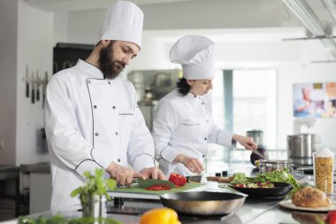 Yetenekli ve kendine güvenen şef garnitür hazırlarken organik ve taze dolma biber doğruyor..